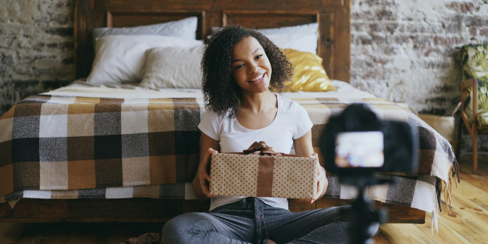 A-girl-sits-by-her-bed-with-a-festive-present-during-an-unboxing-video