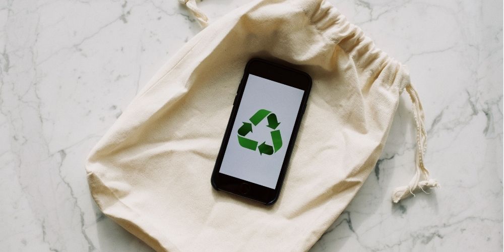 A-phone-with-a-recyclable-logo-laying-on-top-of-a-bag